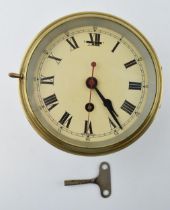A brass cased bulkhead clock with mechanical movement. Made in England, Cream dial with Roman