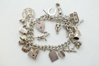 Silver charm bracelet with a church, a bear, people, a tankard and others, 81.6 grams.