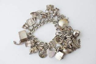 Heavy silver charm bracelet to include an American football, a fish, a boat, a teapot and others,
