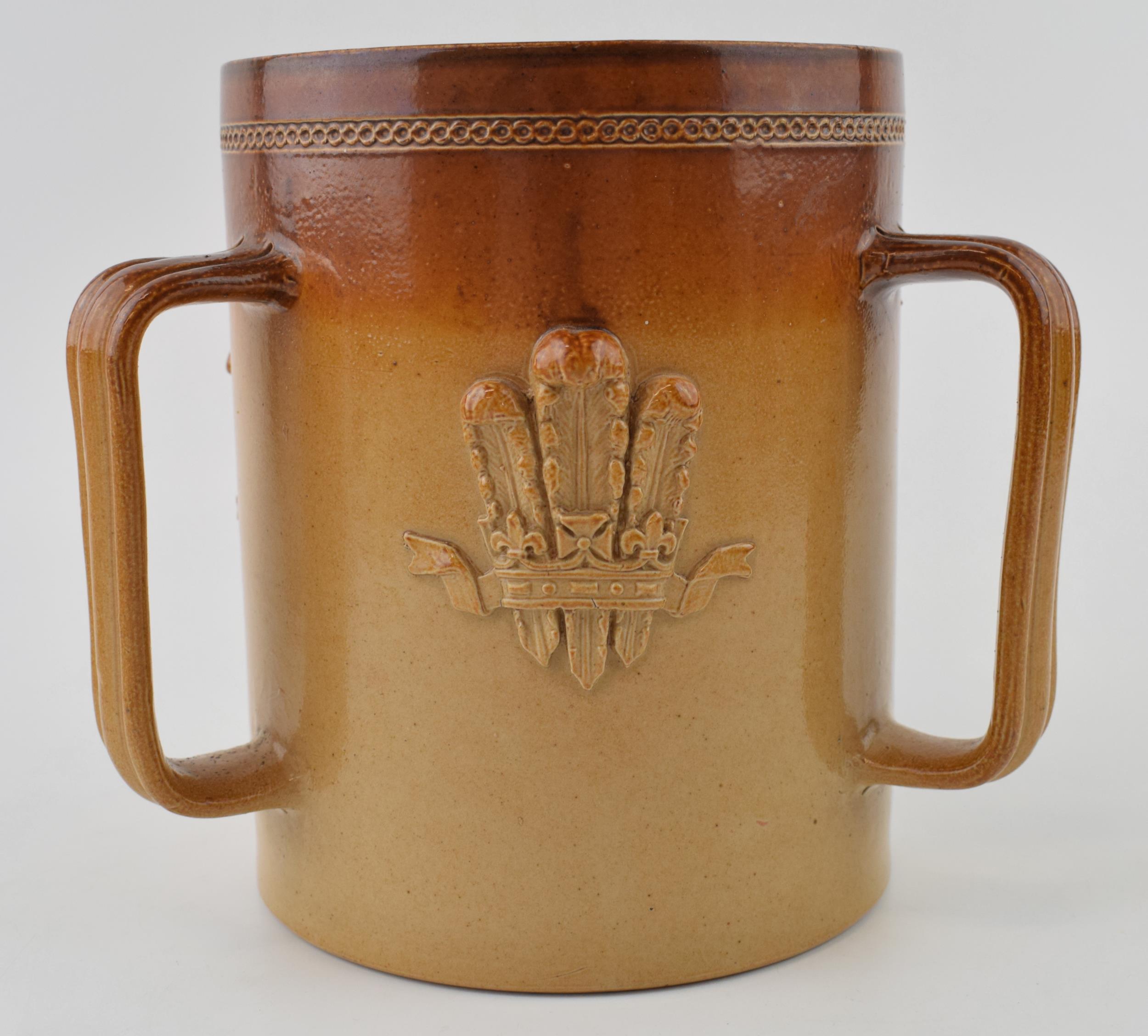 A stoneware loving cup with Fleur-de-lis design. Marked 'Doulton Lambeth' to base with 'John