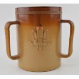A stoneware loving cup with Fleur-de-lis design. Marked 'Doulton Lambeth' to base with 'John