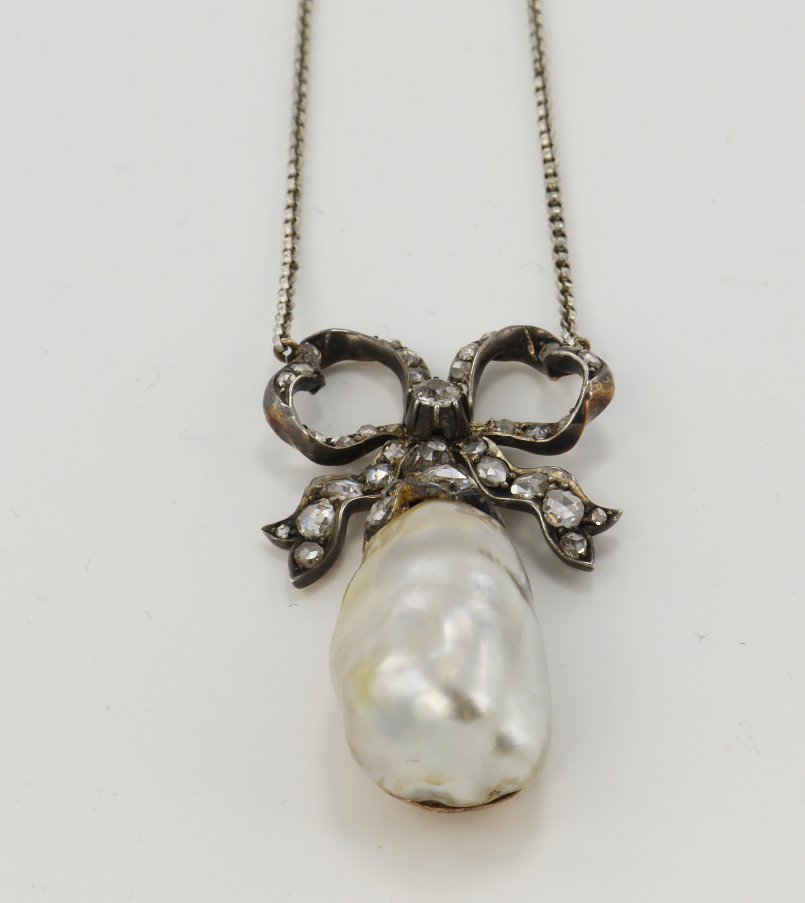 A Victorian diamond and natural saltwater pearl necklace, (tests 8ct) gold backed silver bow set