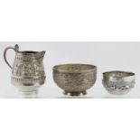 Three pieces of unmarked Indian silver comprising a decorated cream jug & sugar bowl + another small