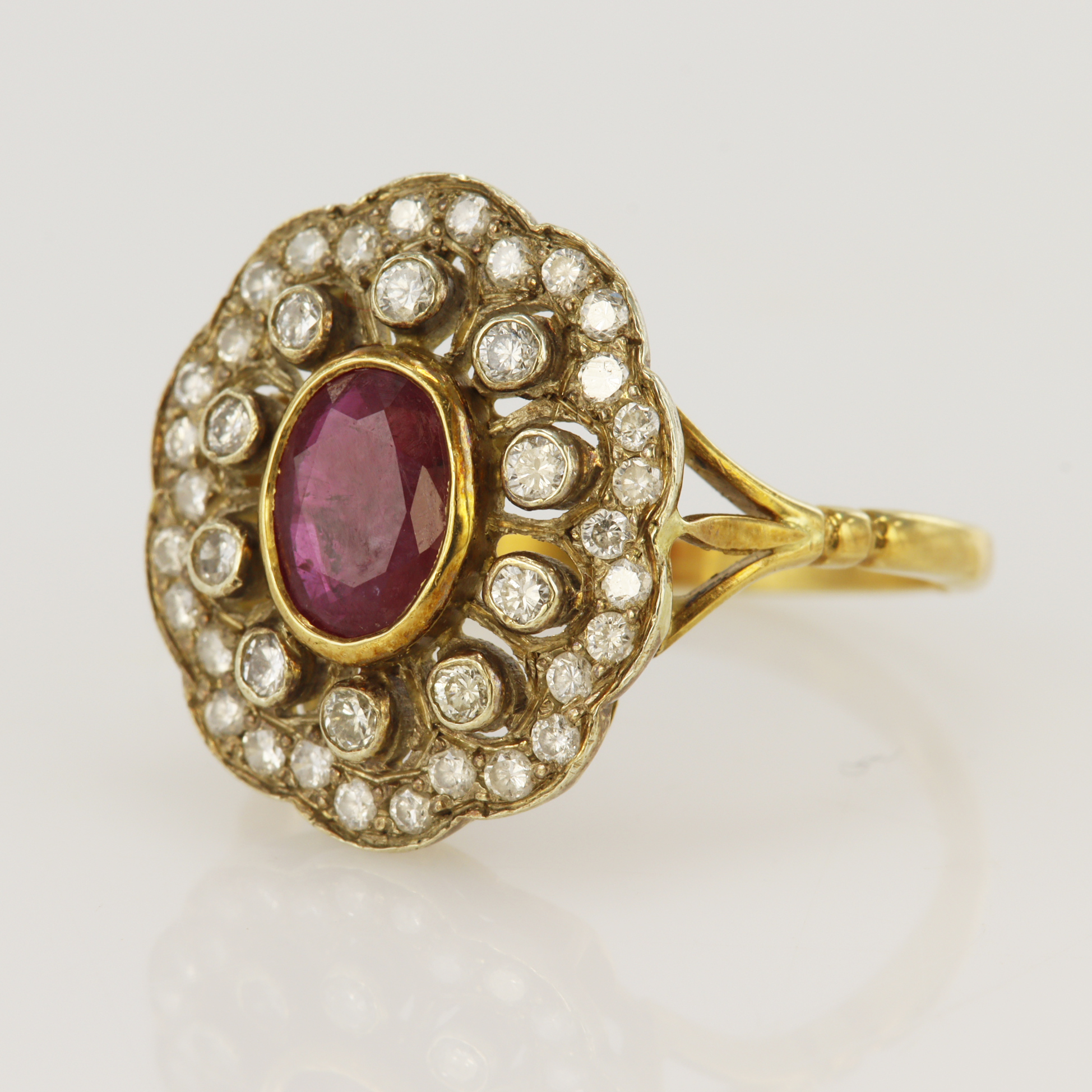 18ct yellow gold diamond and ruby cluster ring, one oval ruby measuring approx. 7 x 5mm,