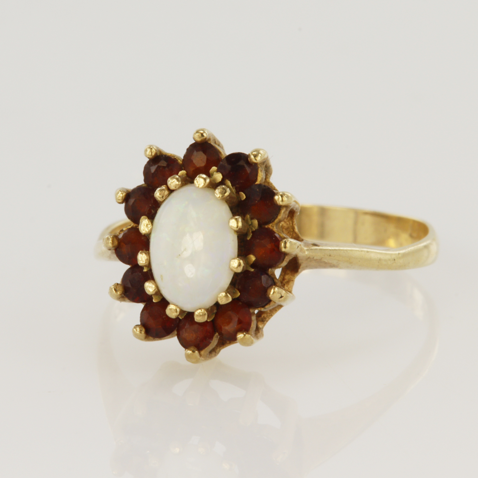 9ct yellow gold cluster ring set with a central oval opal measuring approx. 7mm x 5mm surrounded