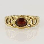 9ct yellow gold garnet Celtic ring, oval garnet measures 7 x 5mm, head width 8.5mm, finger size W,