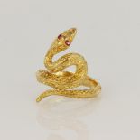 Tests as high carat yellow gold ring depicting a coiled snake with ruby eyes and textured skin,
