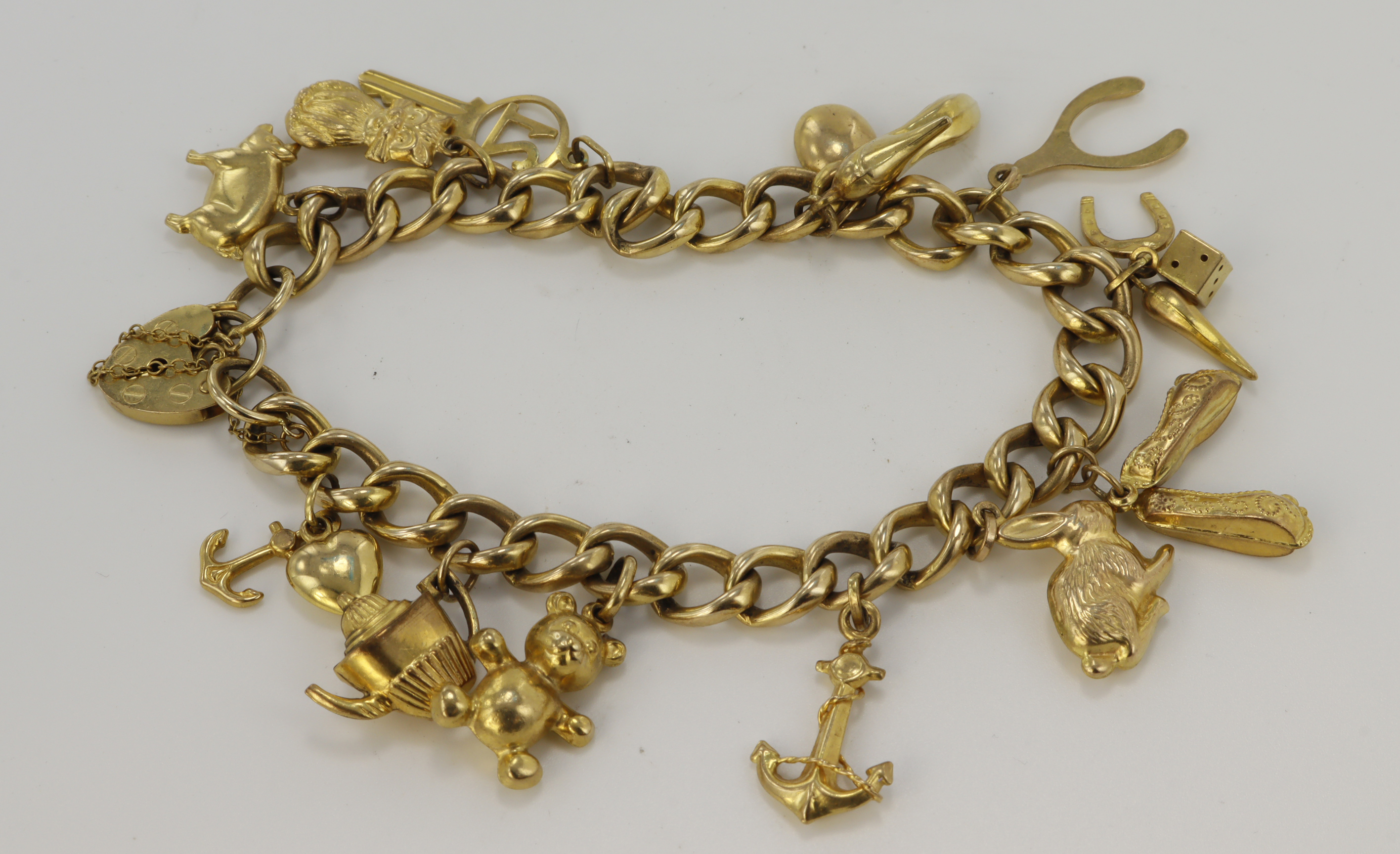 9ct yellow gold charm bracelet with heart padlock clasp, thirteen charms attached, bracelet length