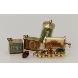 Five 9ct yellow gold vintage novelty charms, four case shilling charms and a paste set traffic light