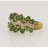 9ct yellow gold dress ring set with sixteen round 3mm diameter emeralds either side of a wave of 9ct