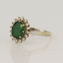White gold (tests 18ct) diamond and emerald cluster ring, one oval emerald measuring 8x7mm,