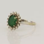 White gold (tests 18ct) diamond and emerald cluster ring, one oval emerald measuring 8x7mm,