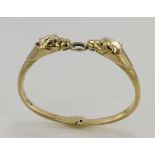 Stamped 14ct yellow gold hinged bangle depicting two panther heads with emerald eyes holding a white