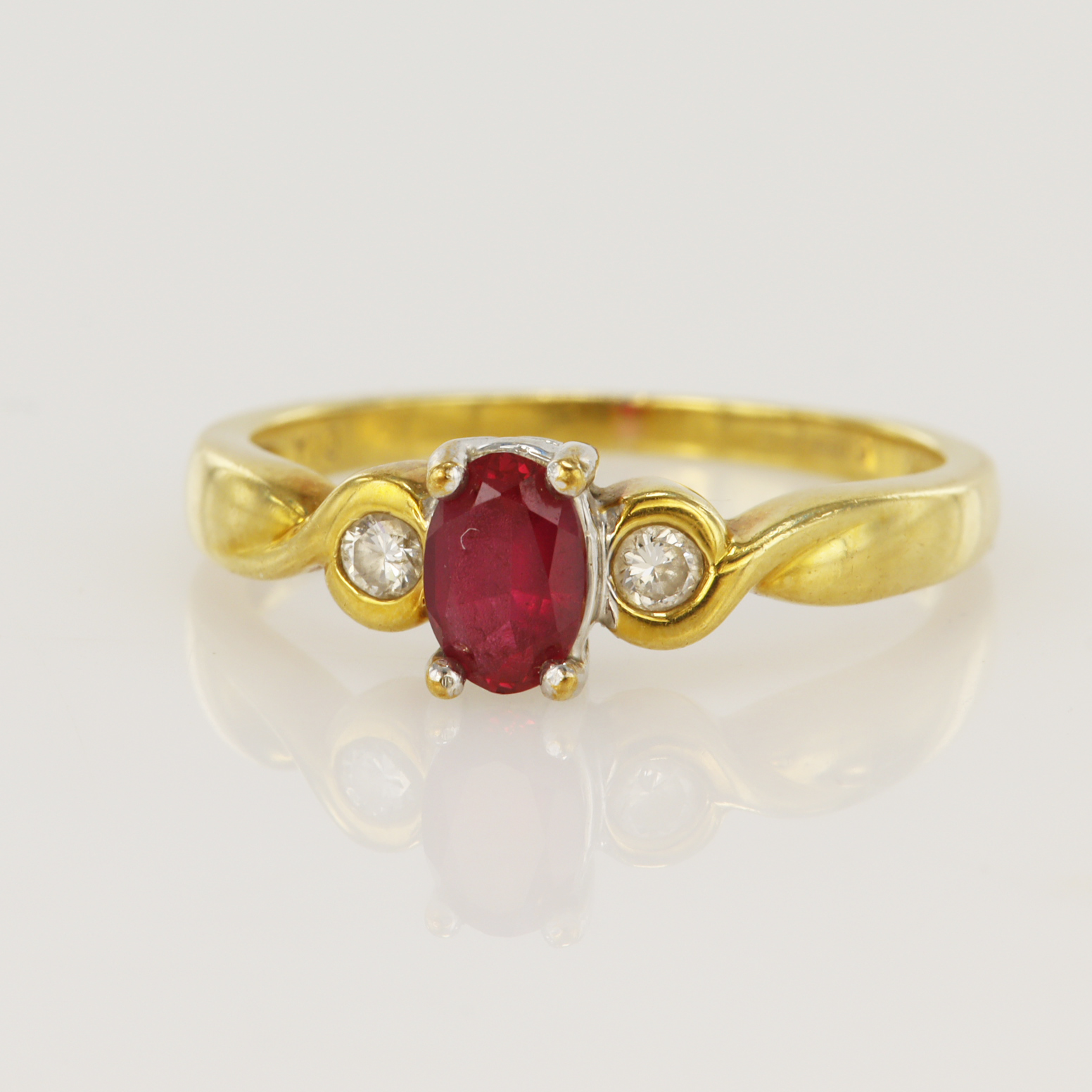 18ct yellow gold diamond and ruby trilogy ring, one oval ruby measuring 6x4mm, two round brilliant