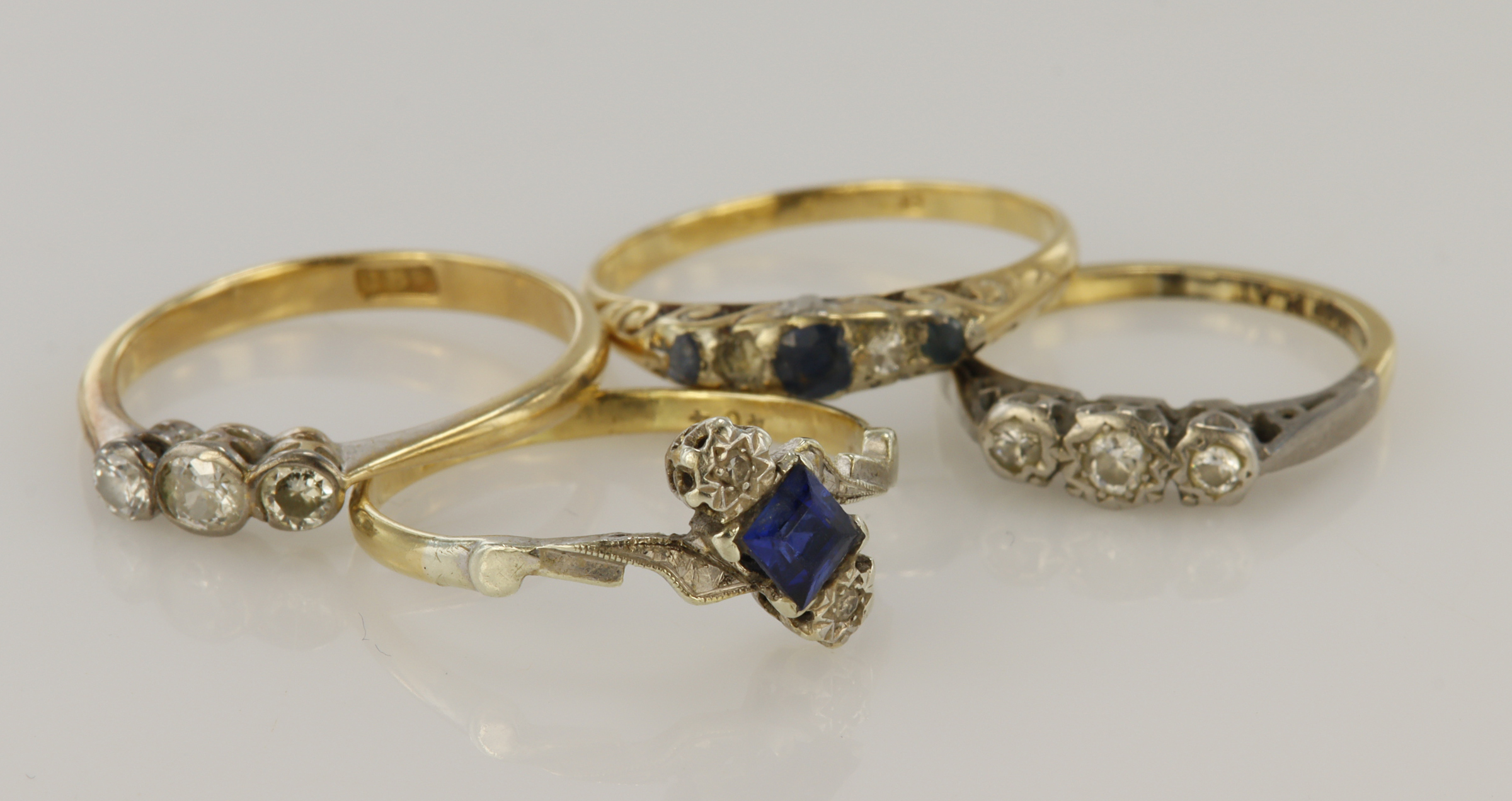 Four yellow gold (tests 18ct) rings, stones include diamond, sapphire, blue paste, finger sizes J,