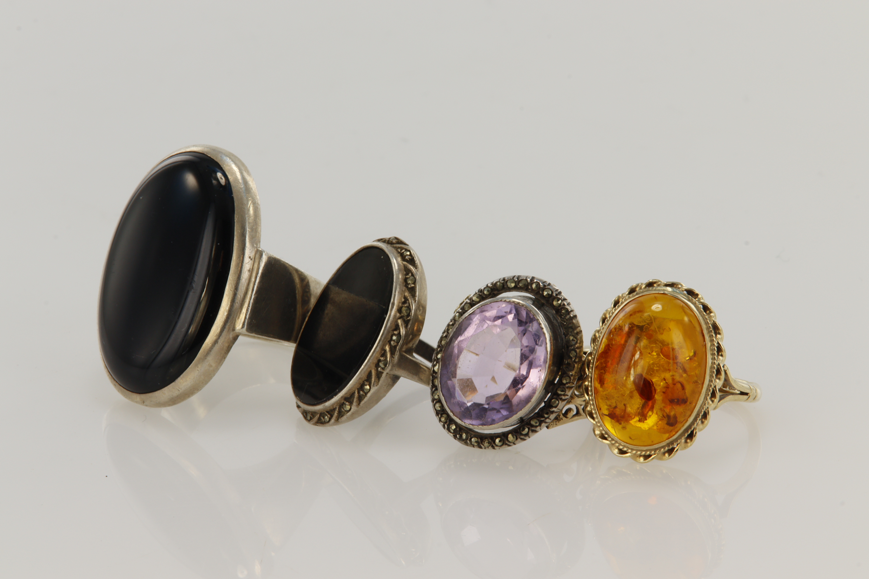 Four rings, one 9ct gold and amber ring, amber measures 17 x 12mm, finger size Q/R. Yellow gold (