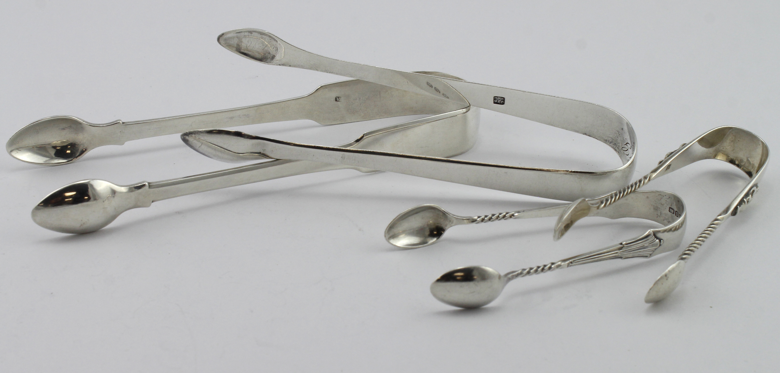 Four pairs of silver sugar tongs comprising two Geo III pairs hallmarked London 1807 & 1813 & two