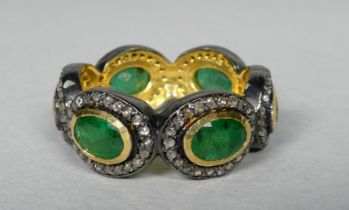 A full eternity ring set with oval emeralds - each emerald surrounded by a halo of diamonds, the