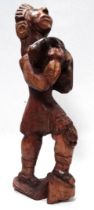 A 20th century carved hardwood figure of a Mayan Indian - wearing feathered headband and holding a