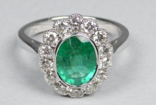 An 18ct white gold ring set an emerald and diamonds - the central oval emerald weighing 1.08ct
