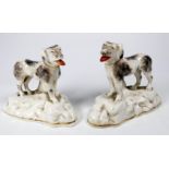 A pair of Chelsea style models of dogs - standing on a rocky base, sponge decorated, with a gilt