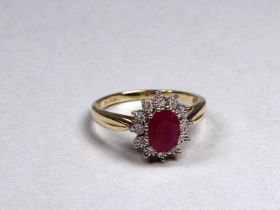 A 9ct yellow gold ruby and diamond set cluster ring - the central oval treated ruby weighing 0.