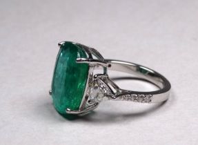 An 18ct white gold emerald and diamond set trilogy ring - with a central oval cushion and mixed