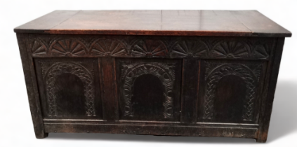 A 17th century and later oak coffer - the associated plank top above carved triple panel front and