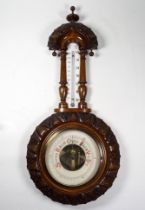 A late 19th century stained beech aneroid barometer - leaf carved incorporating a thermometer,