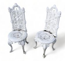 A pair of cast iron garden chairs - painted white, the backs incorporating an oval cartouche