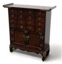 A 20th century Chinese elm table cabinet - of typical form with an arrangement of sixteen drawers