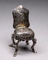 A white metal doll's house chair - repousse decorated and raised on cabriole legs, purity stamp to