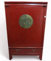 A Chinese red lacquered cabinet - the pair of panel doors with impressive brass circular