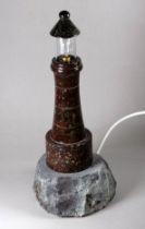 A Cornish turned serpentine table lamp in the form of a lighthouse - mounted on a rocky base