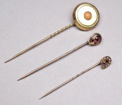 A gilt metal stock pin - set with a pink coral bead, together with two further stock pins, weight
