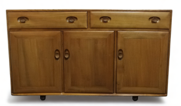 An Ercol elm sideboard - of Windsor pattern with a pair of drawers above panel doors, one