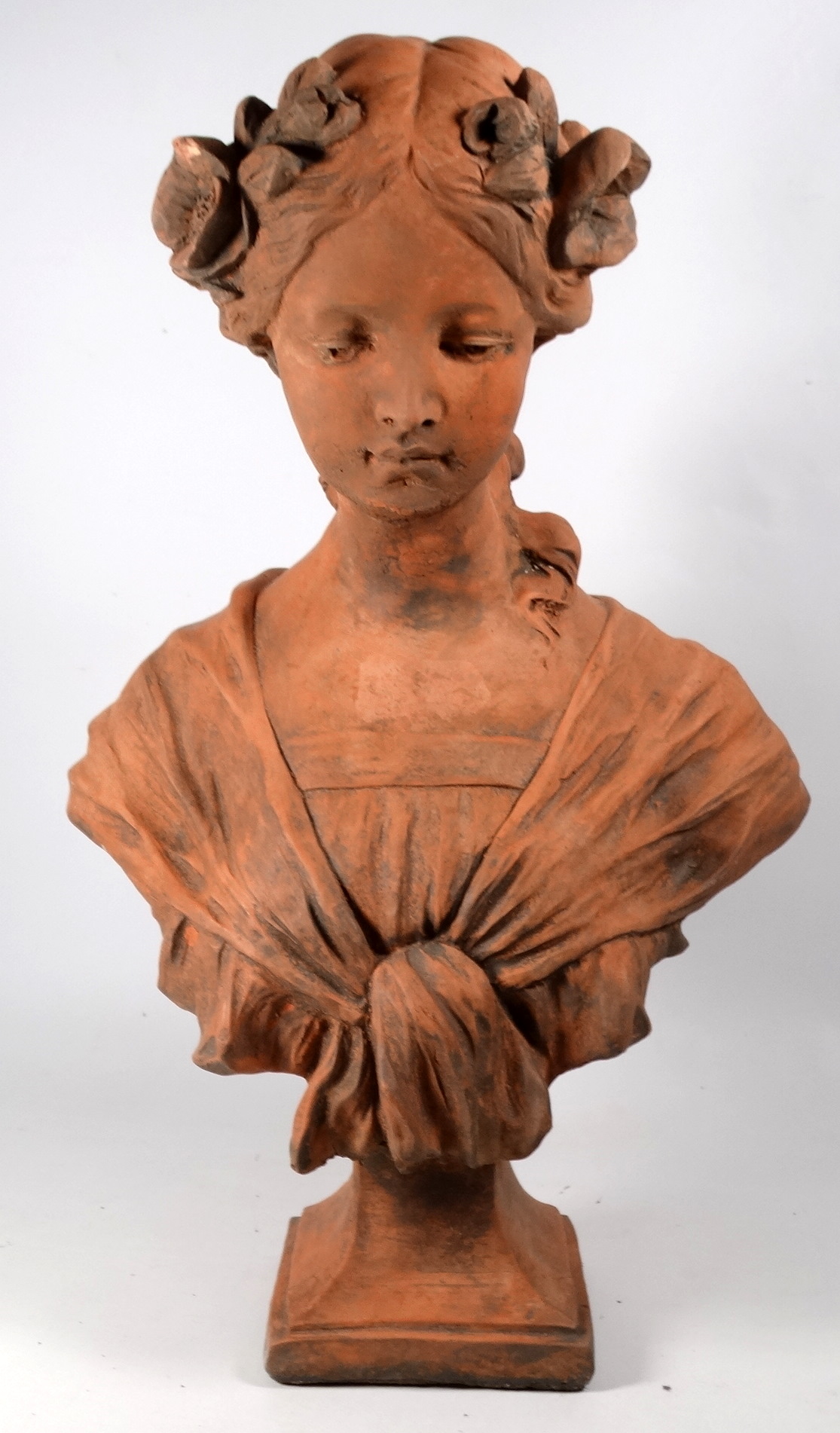 A Neoclassical terracotta female bust - flowers in her hair and raised on a square base, height