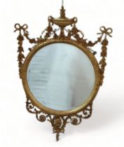 A Victorian gilt gesso wall mirror - an oval bevelled plate with an urn finial and flanked by