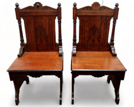 A pair of late Victorian oak Gothic revival hall chairs - with carved panel backs flanked by