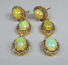 A pair of long triple halo drop opal and diamond earrings - each set with three oval cabochon