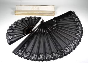 An early 20th century ebony fan - with a black lace web, with retail box, length 36cm, together with