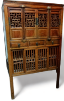 A 19th century Chinese cabinet - with an arrangement of four pierced panel doors above three drawers