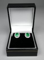 A pair of 18ct white gold emerald and diamond set cluster earrings - the central oval emeralds