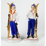 A pair of early 20th century figures - dressed a skiers, standing holding skis, raised on oval