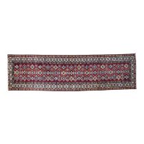A Shirvan runner - with multiple small medallions on a red ground and multi-stripe border, 272 x