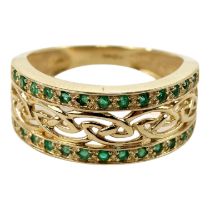 A 14ct gold emerald set dress ring - with a pierced central knot-work band set between stones,