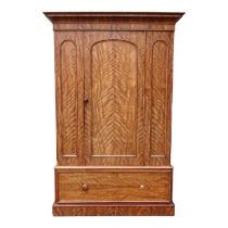 A Victorian satin birch wardrobe - the moulded cornice above an arched panel door, with a drawer