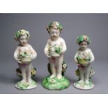 A 19th century German figure of a putto - holding a basket of flowers, height 11cm, together with
