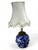 A late 19th century ginger jar converted as a lamp - with blue and white prunus decoration, four
