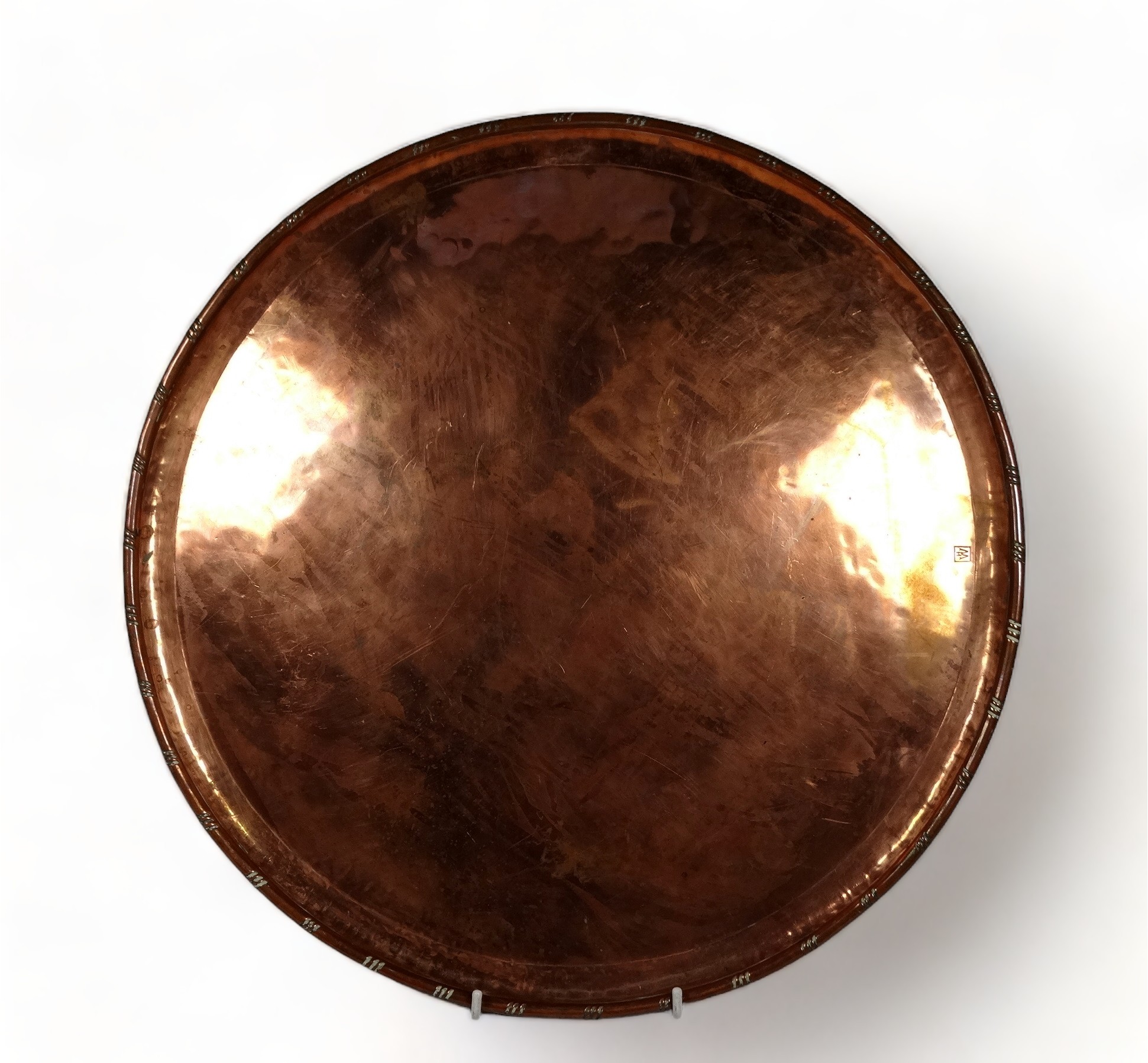 Hugh Wallace (British 1871-1943) a circular copper tray - with a rolled rim, bearing initials within